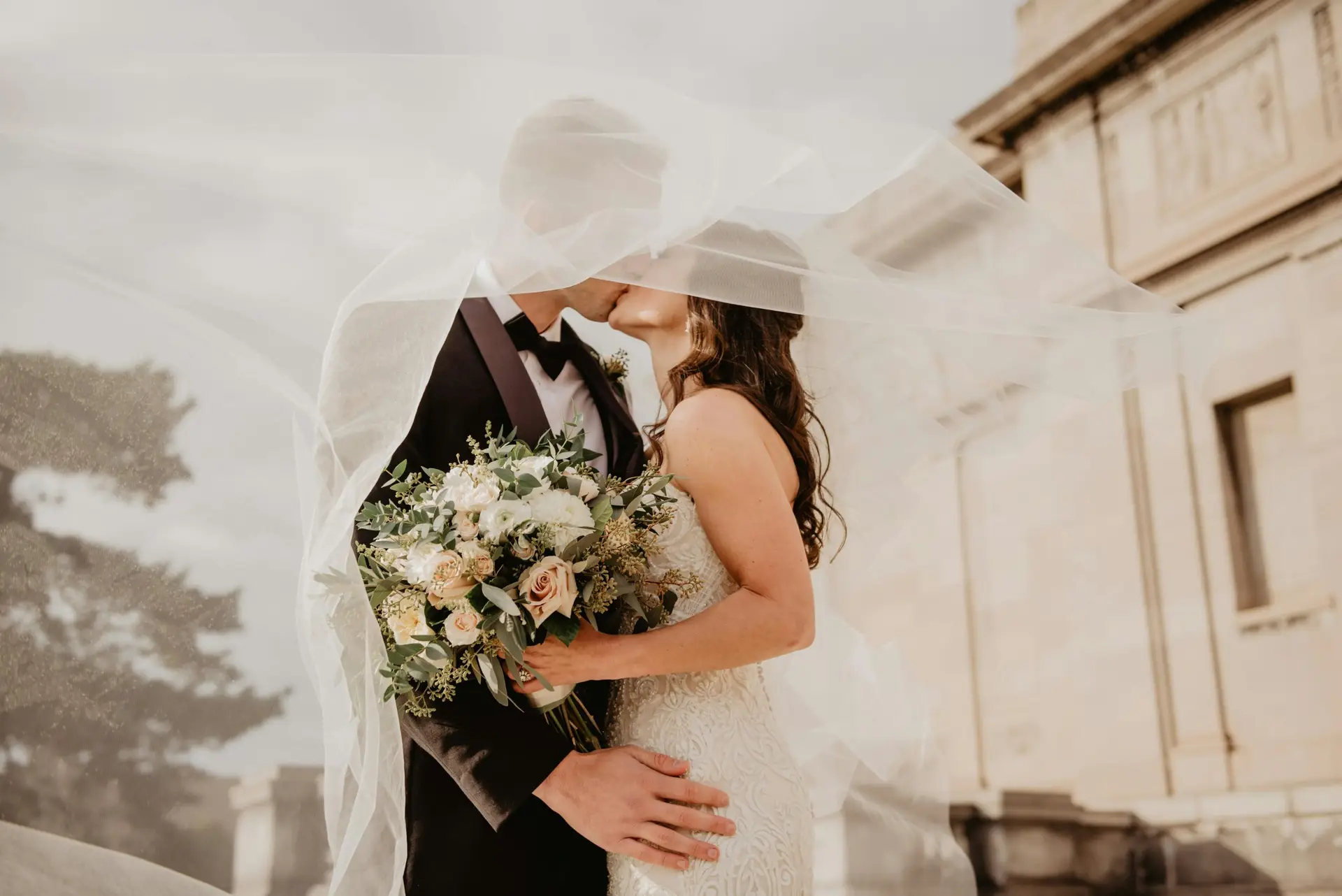 Married couple kissing under veil